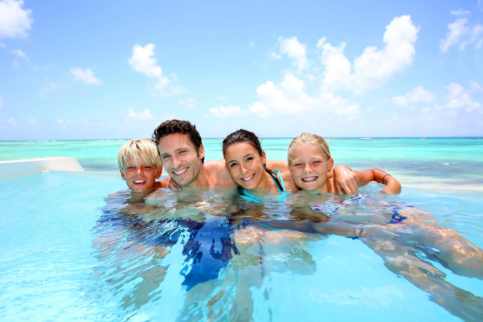 Family swimming in an infinity pool overlooking the reef at Windsong on the Reef.