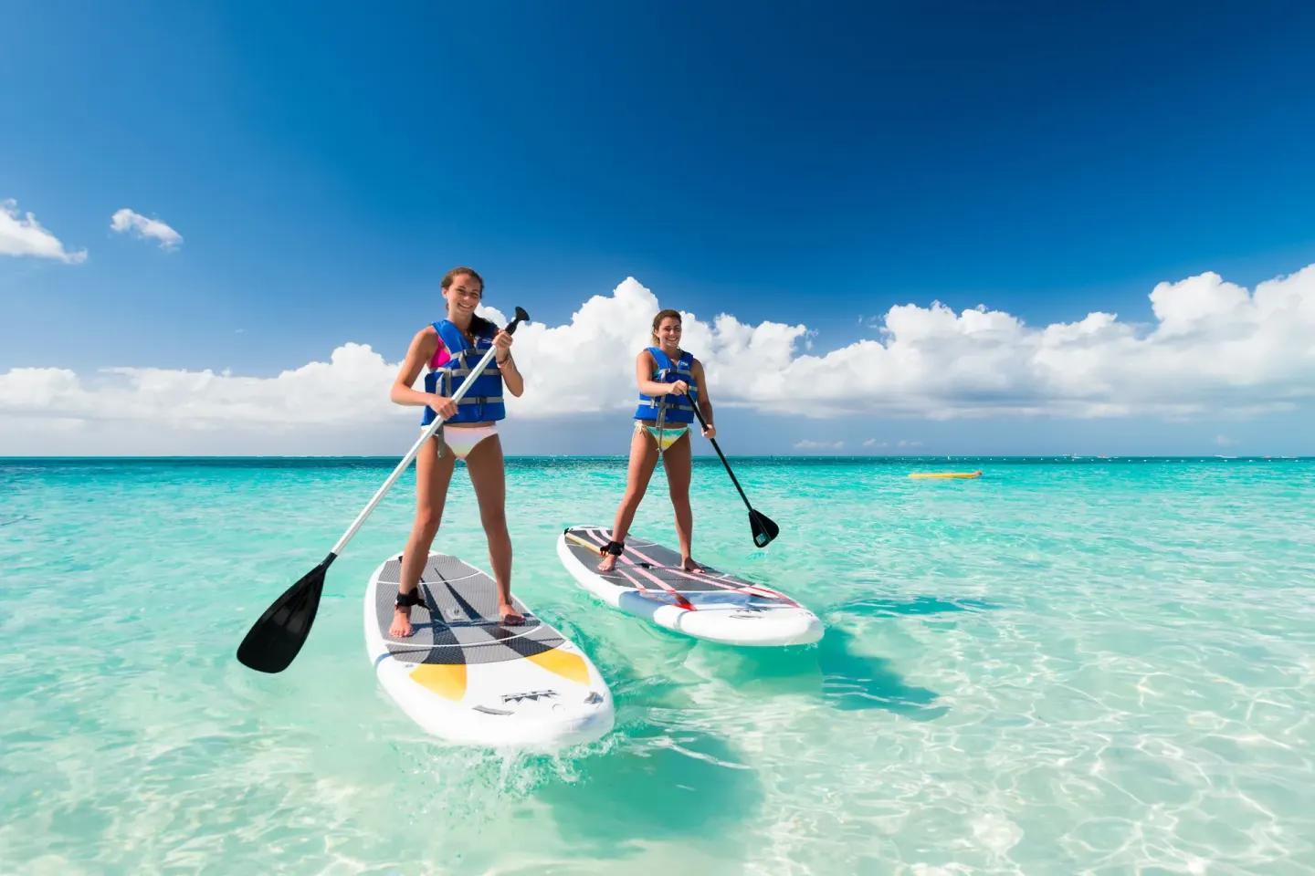 Two paddleboarders stand on turquoise water near Windsong on the Reef.
