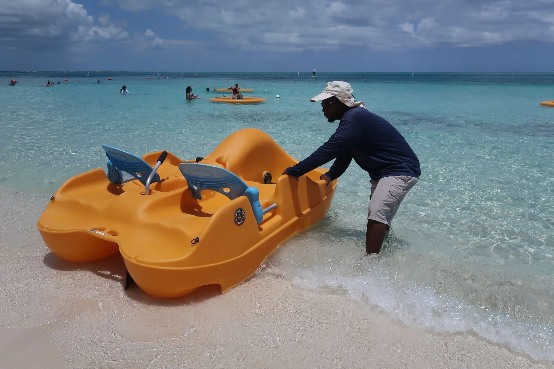A staff member pushes an orange pedal boat into the water at Windsong on the Reef.