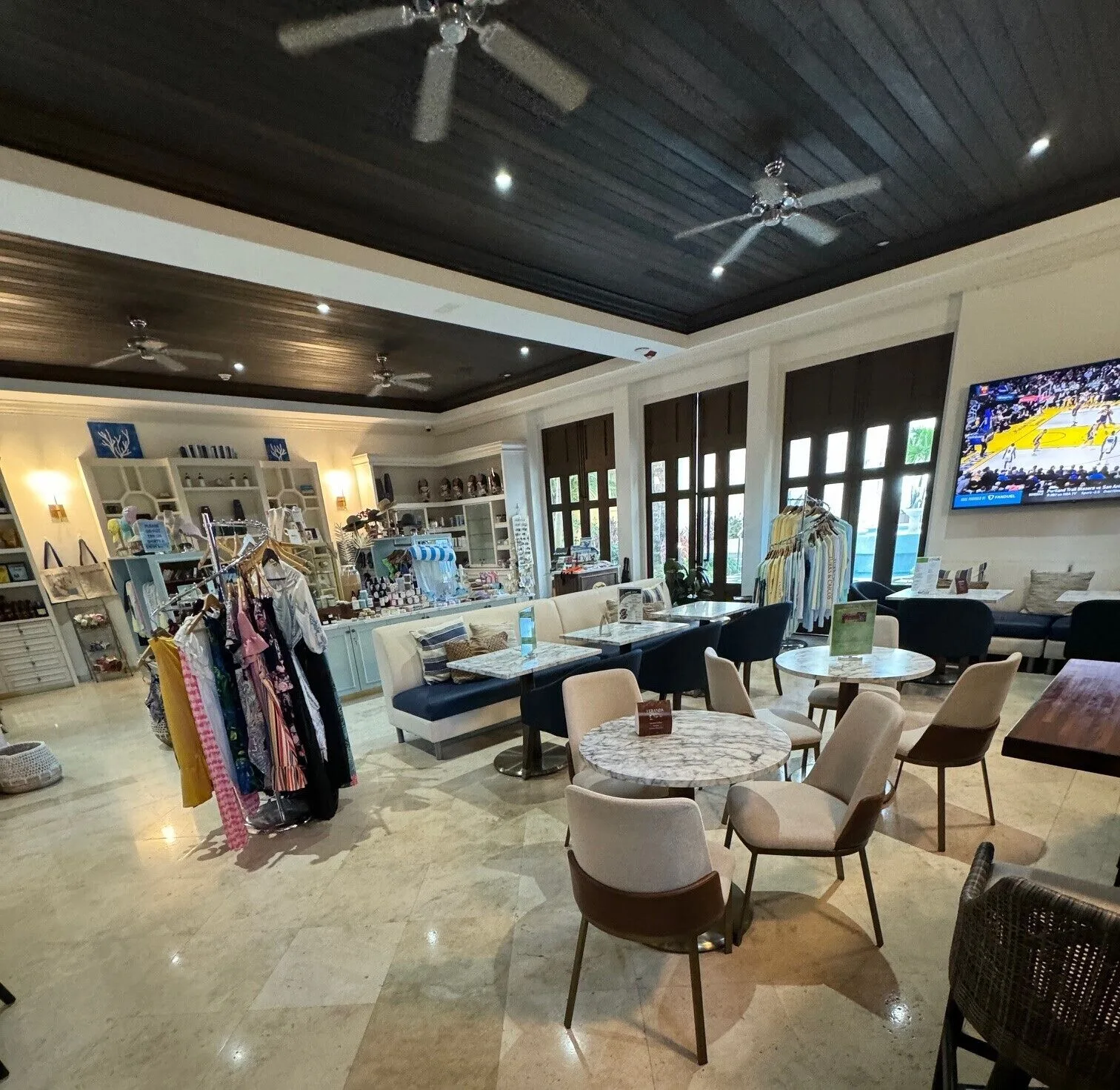Resort lounge with café tables, boutique displays, and seating at Windsong on the Reef.