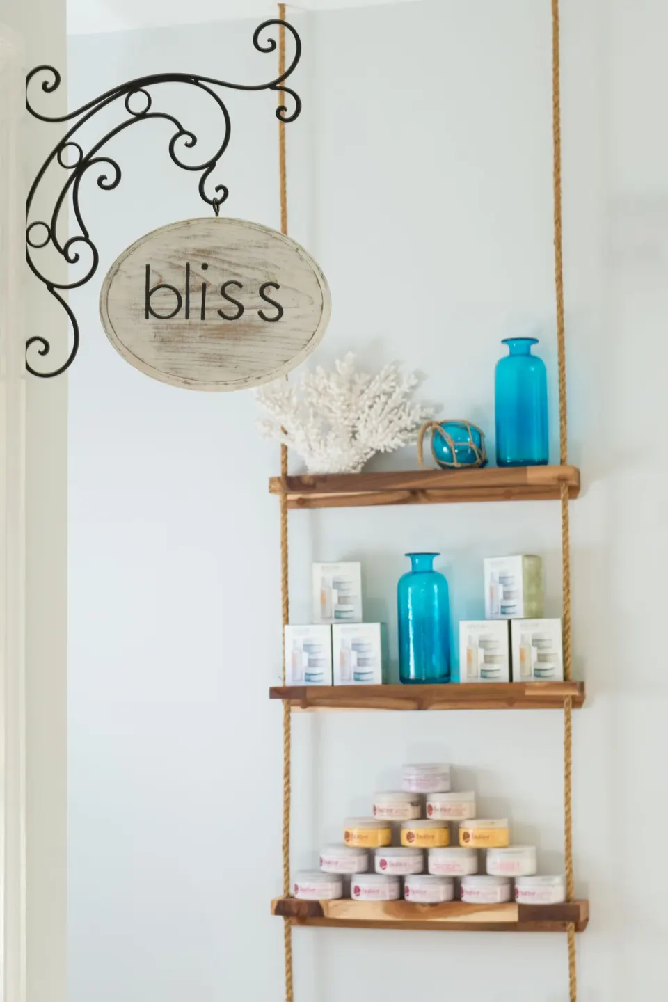 Spa retail shelves with jars, boxes, coral, and blue glass accents at Windsong on the Reef.