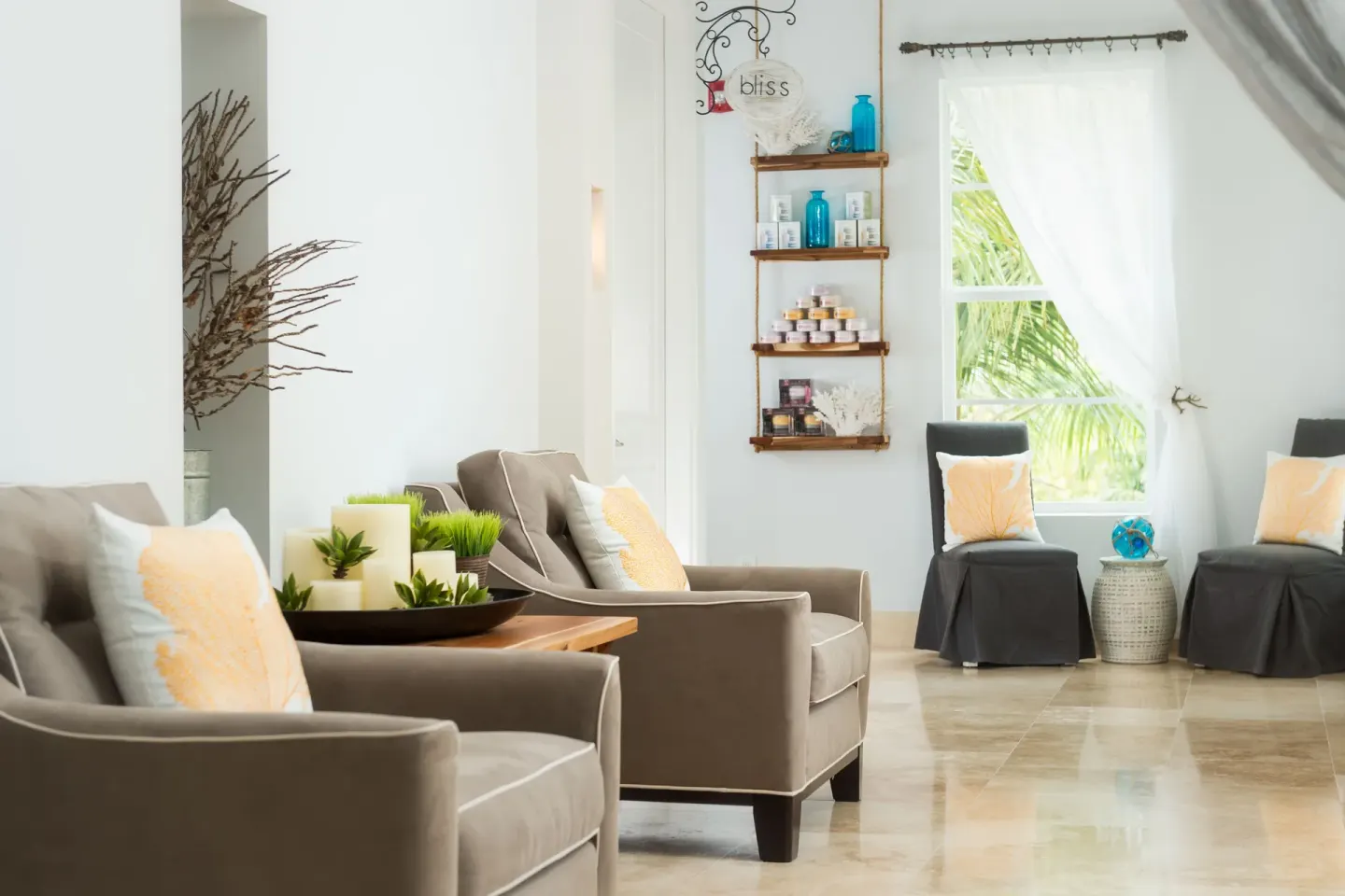 Spa seating area with armchairs, product shelves, and a bright window at Windsong on the Reef.