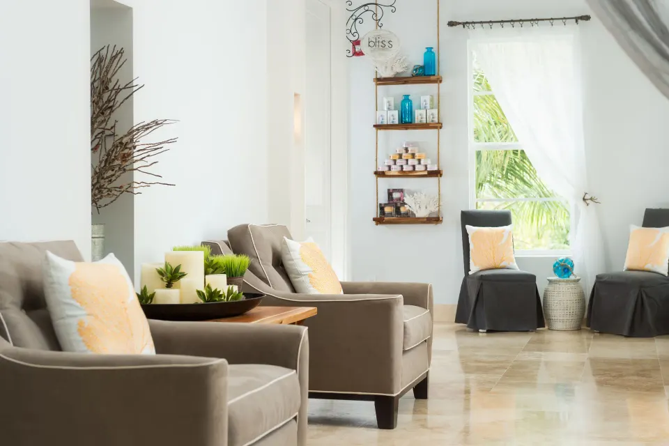 Spa seating area with armchairs, product shelves, and a bright window at Windsong on the Reef.
