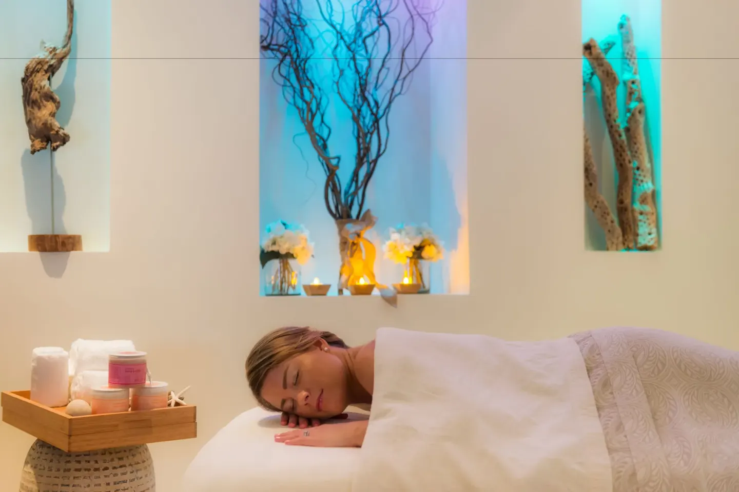 Guest lying under a white cover on a spa treatment table at Windsong on the Reef.