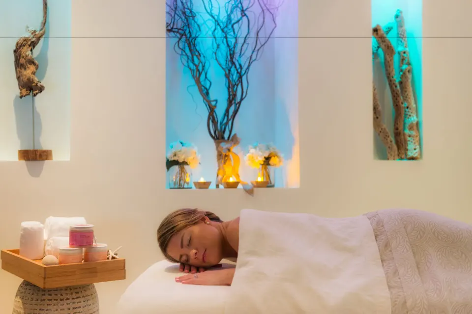 Guest lying under a white cover on a spa treatment table at Windsong on the Reef.