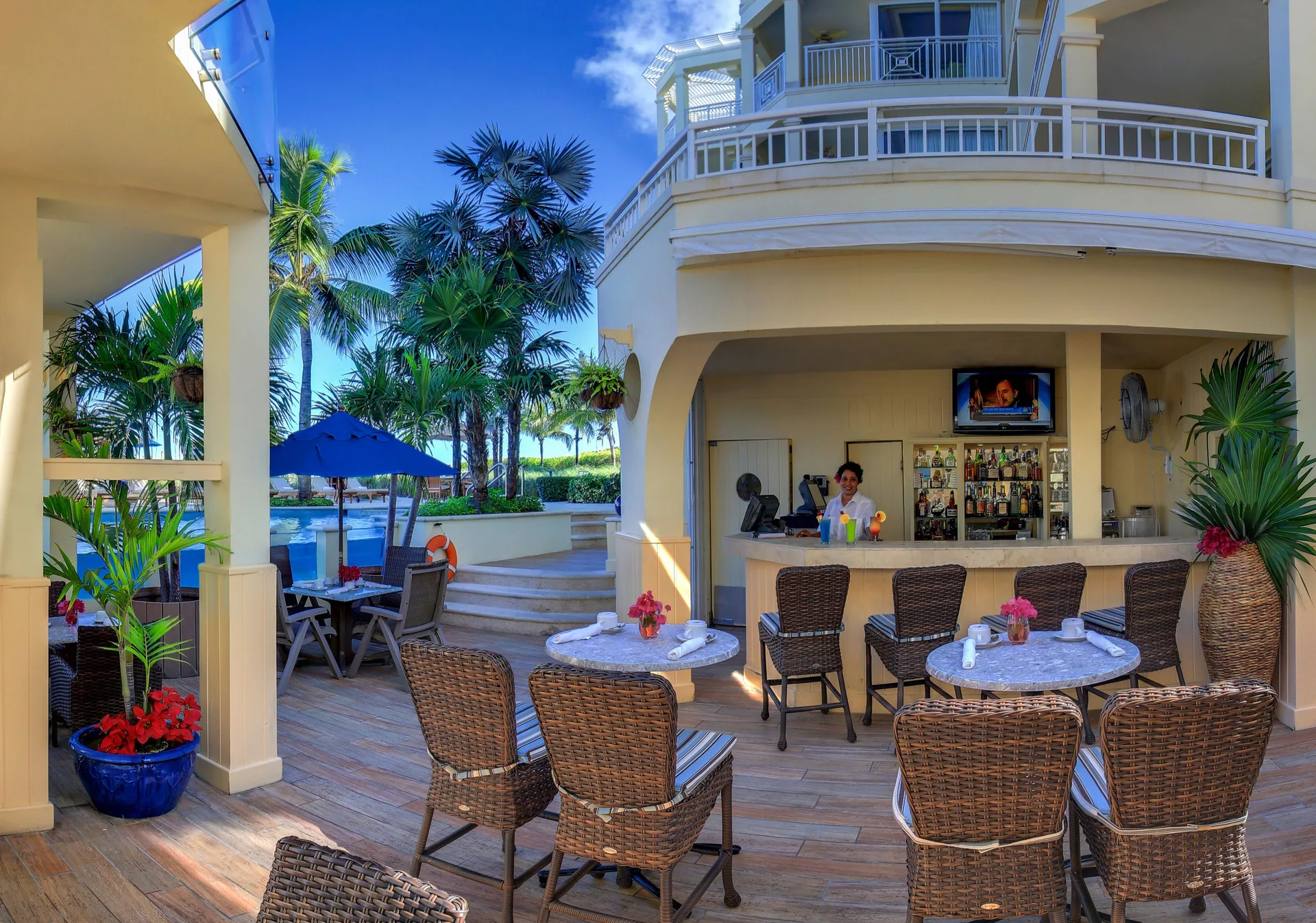 Poolside bar with wicker seating and resort buildings at Windsong on the Reef.