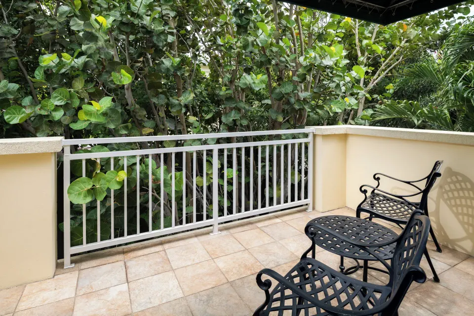 Private balcony with metal chairs in a Bungalow 1 Bedroom at Windsong on the Reef.