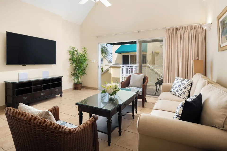 Living area with sofa, TV, and balcony access in a Bungalow 1 Bedroom at Windsong on the Reef.