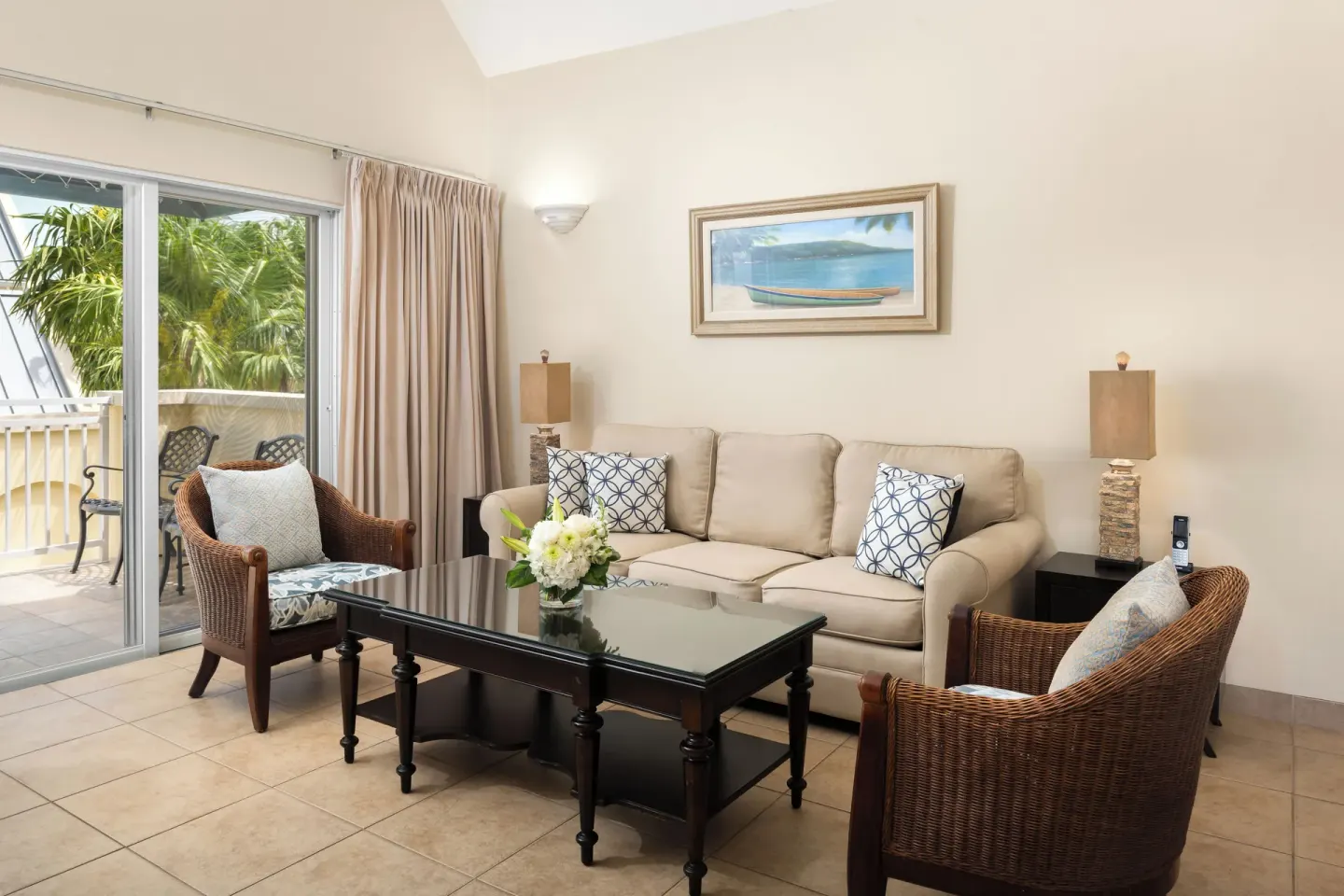 Living room seating and balcony doors in a Bungalow 1 Bedroom at Windsong on the Reef.