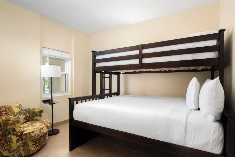 Bungalow bedroom with bunk bed and chair at Windsong on the Reef.