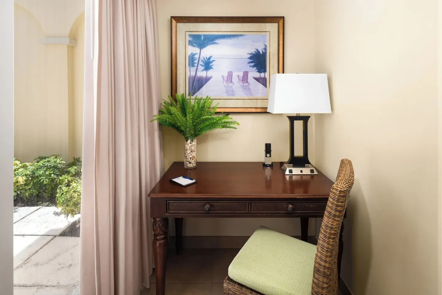 Bungalow desk beside patio curtains and greenery at Windsong on the Reef.