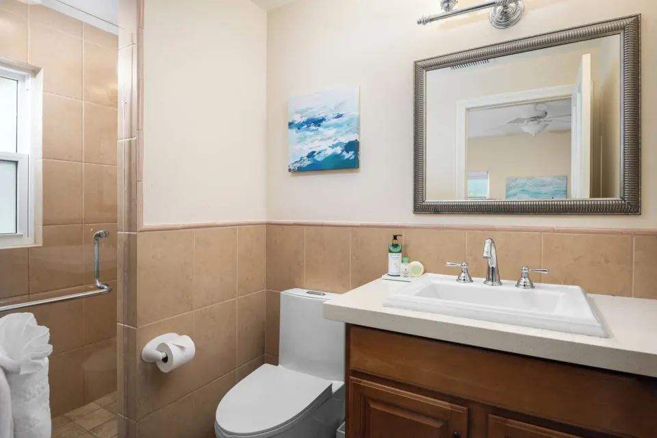 Bungalow bathroom with vanity, toilet and tiled shower at Windsong on the Reef.