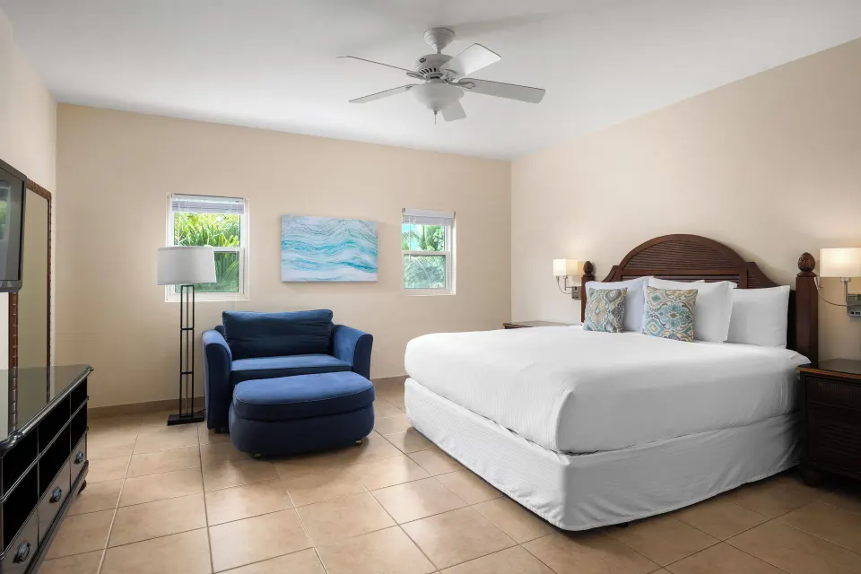 Bungalow three-bedroom king bedroom with blue chair at Windsong on the Reef.