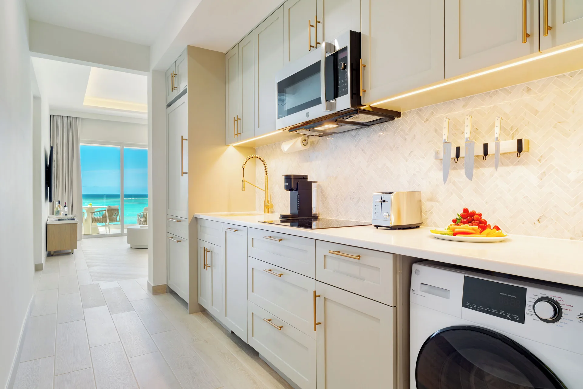 Junior Suite kitchenette with laundry and ocean view beyond at Windsong on the Reef.
