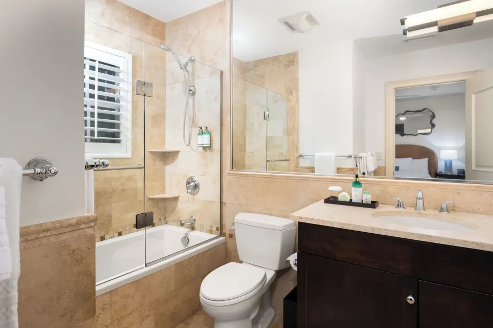 Studio bathroom with glass tub shower and vanity at Windsong on the Reef.