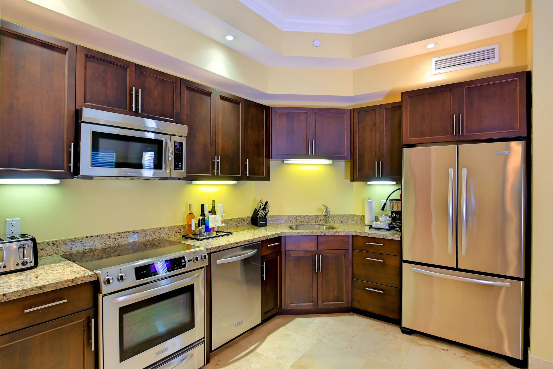 One Bedroom Suite kitchen with stainless appliances and wood cabinets at Windsong on the Reef.