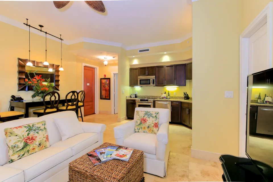 One Bedroom Suite seating area with sofa, armchair, dining table, and kitchen at Windsong on the Reef.