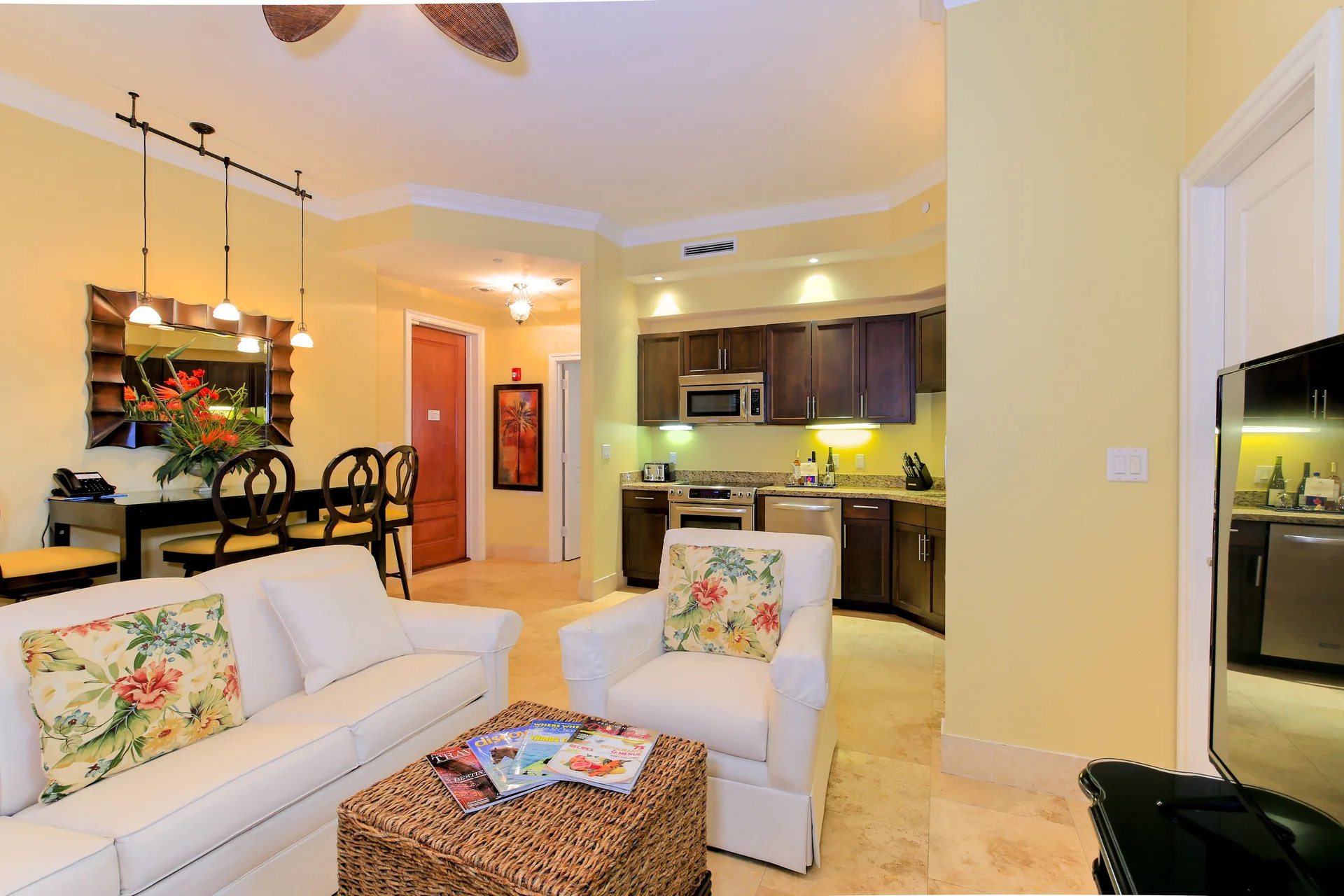 One Bedroom Suite seating area with sofa, armchair, dining table, and kitchen at Windsong on the Reef.