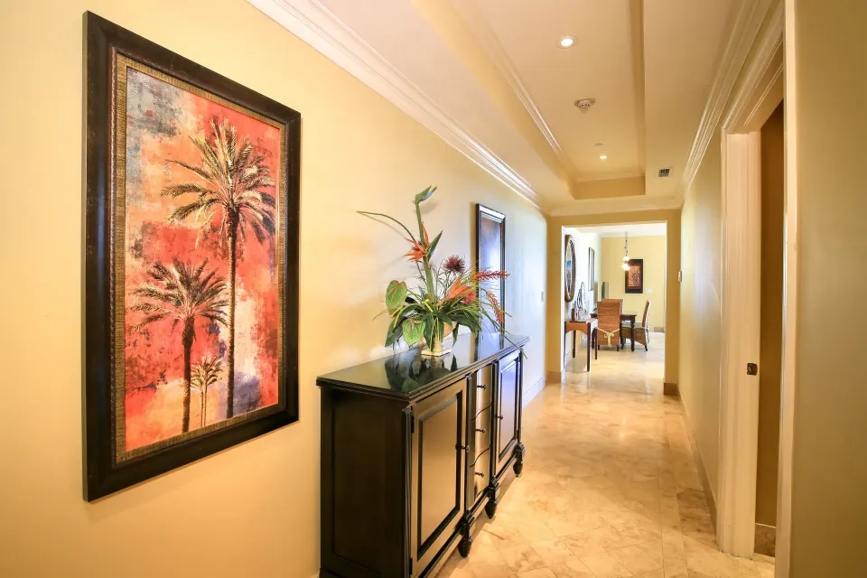 Oceanfront suite hallway with palm artwork, console, and flowers at Windsong on the Reef.
