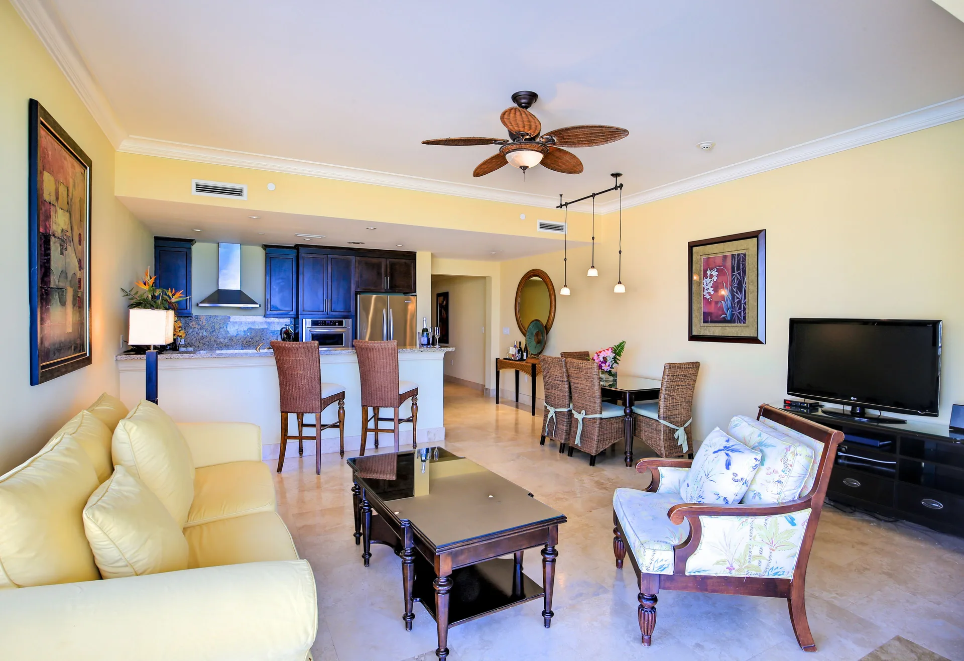 Oceanfront suite living room with kitchen, dining area, sofa, and TV at Windsong on the Reef.