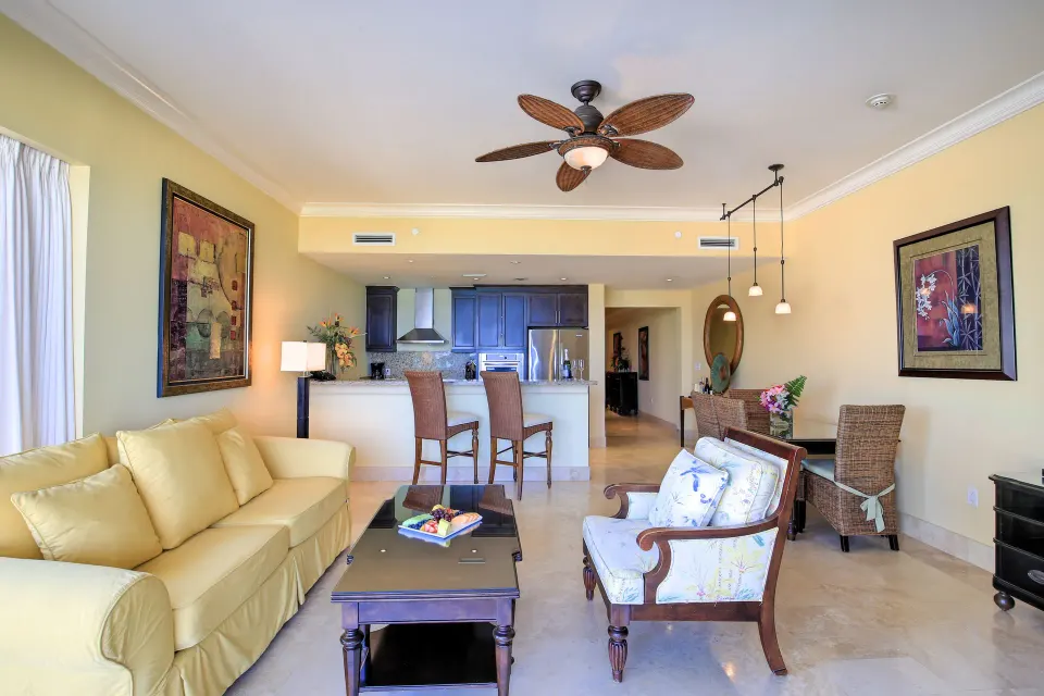 Oceanfront suite living room with sofa, armchair, kitchen bar, and dining table at Windsong on the Reef.