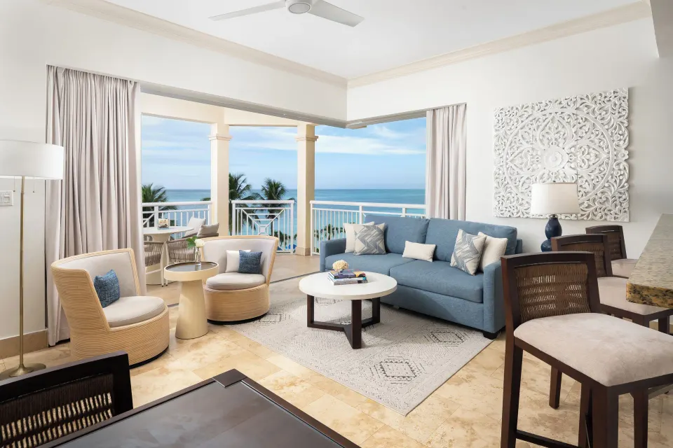 Oceanfront suite sitting area with blue sofa and balcony sea view at Windsong on the Reef.