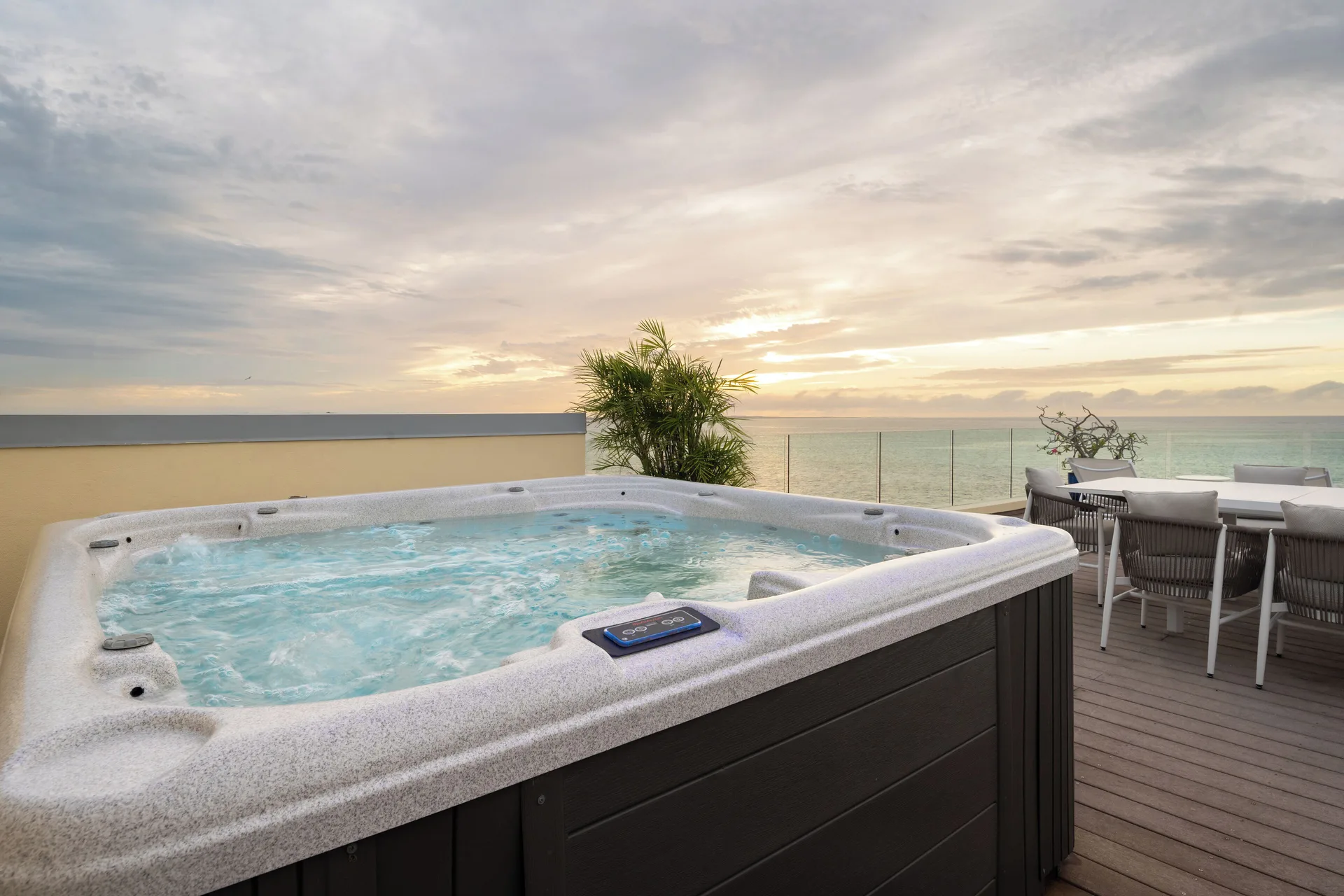 Oceanfront villa terrace hot tub at Windsong on the Reef with sunset sea view.
