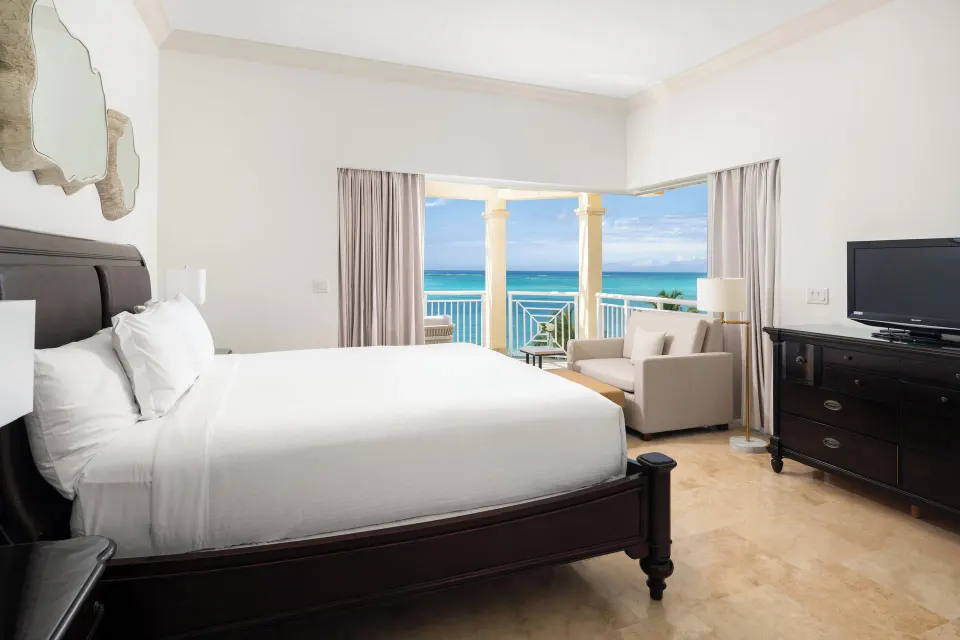 Oceanfront villa bedroom with king bed and balcony view at Windsong on the Reef.