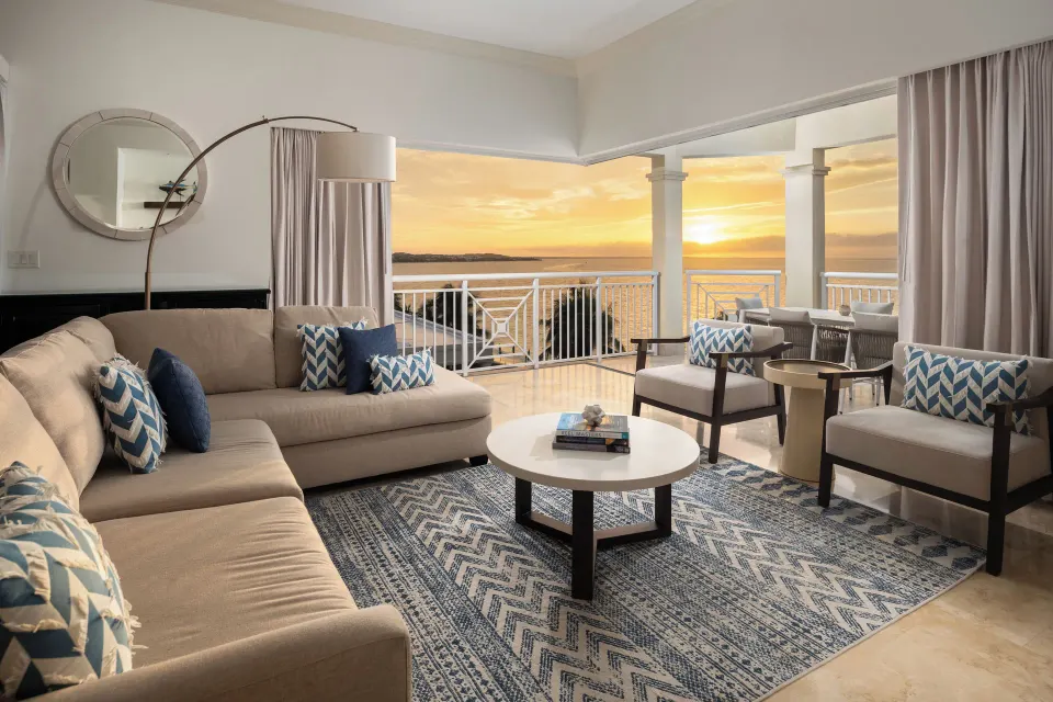 Oceanfront villa living room and terrace at Windsong on the Reef with sunset water views.