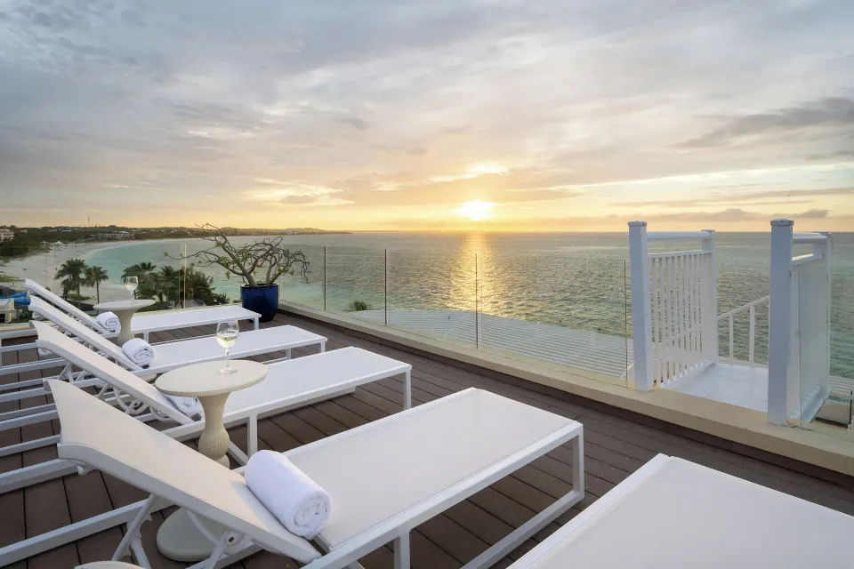 Oceanfront villa terrace loungers at sunset at Windsong on the Reef.