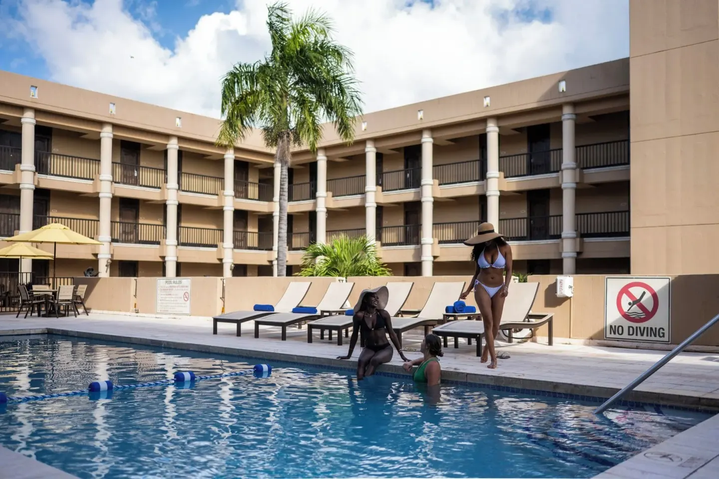 Guests gather by the courtyard pool with loungers behind them at Windward Passage Hotel.
