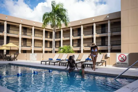 Guests gather by the courtyard pool with loungers behind them at Windward Passage Hotel.