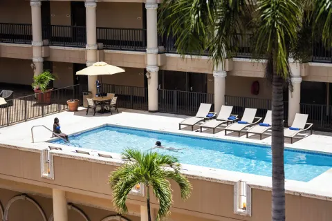 Guests swim in the courtyard pool beneath palm trees at Windward Passage Hotel.
