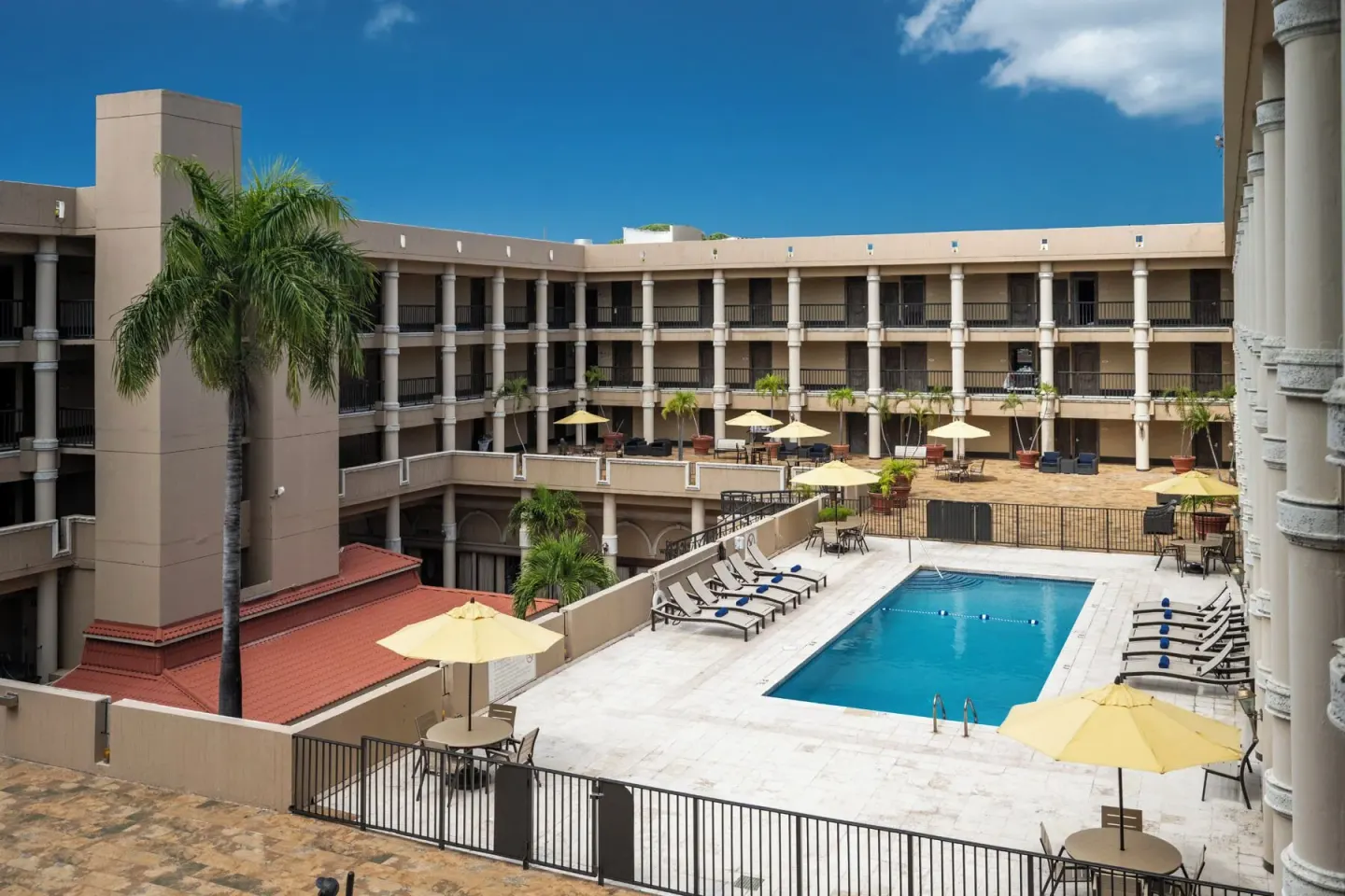 Courtyard pool with palms, umbrellas, and balconies at Windward Passage Hotel.