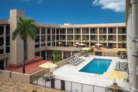 Courtyard pool with palms, umbrellas, and balconies at Windward Passage Hotel.