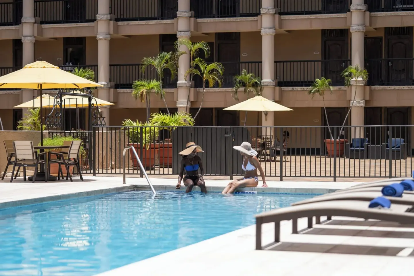 Two guests sit at the pool edge at Windward Passage Hotel.