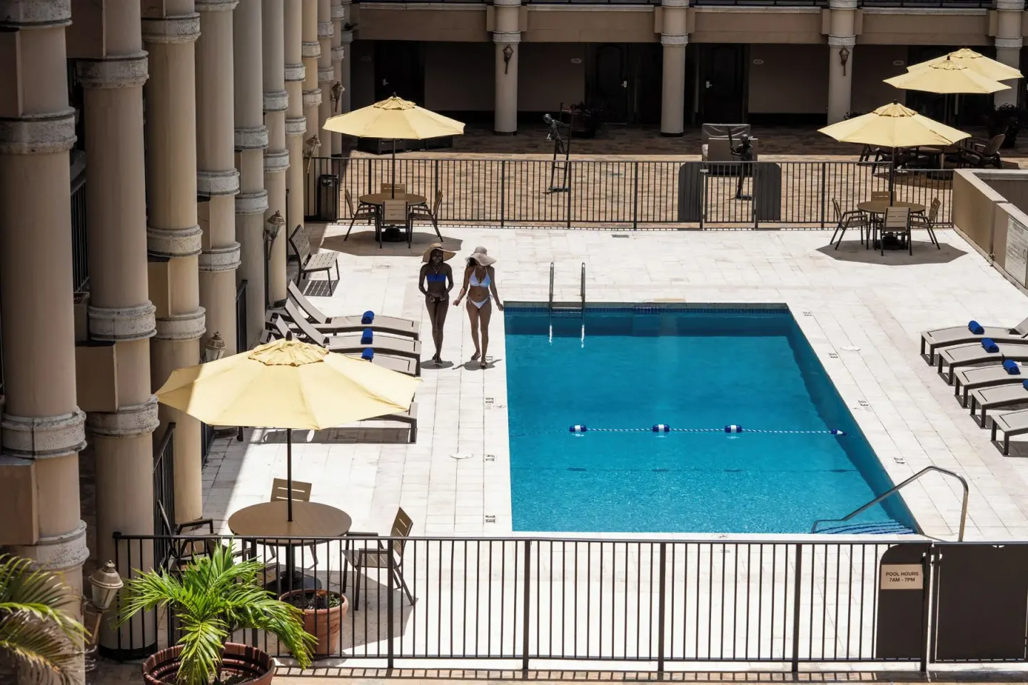 Two guests walk beside the courtyard pool at Windward Passage Hotel.