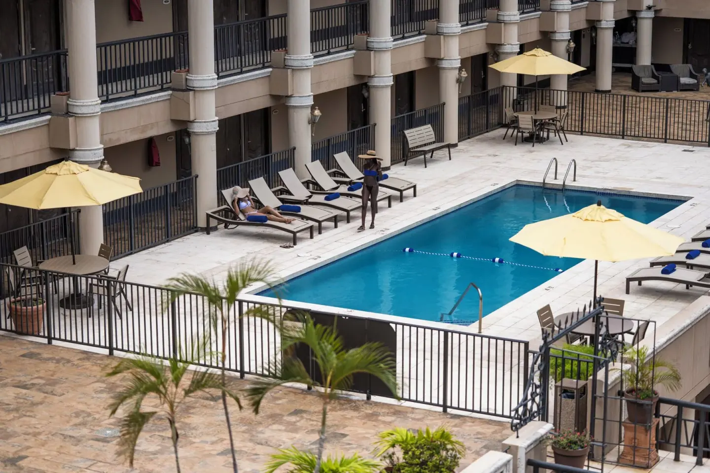 A guest stands near loungers beside the pool at Windward Passage Hotel.
