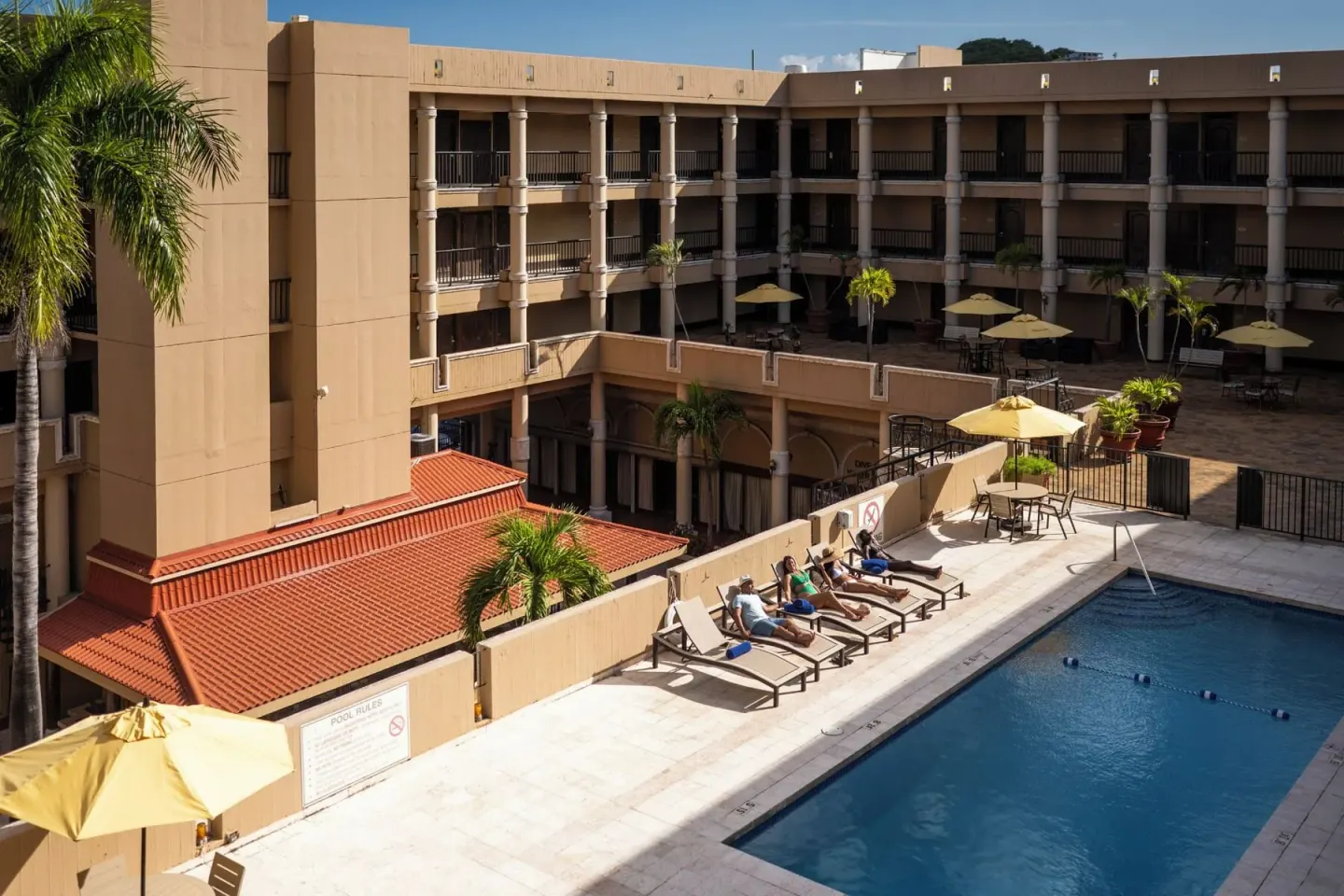 Pool deck with loungers, umbrellas, and balconies at Windward Passage Hotel.
