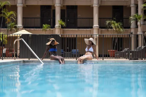 Two guests sit at the pool edge at Windward Passage Hotel.