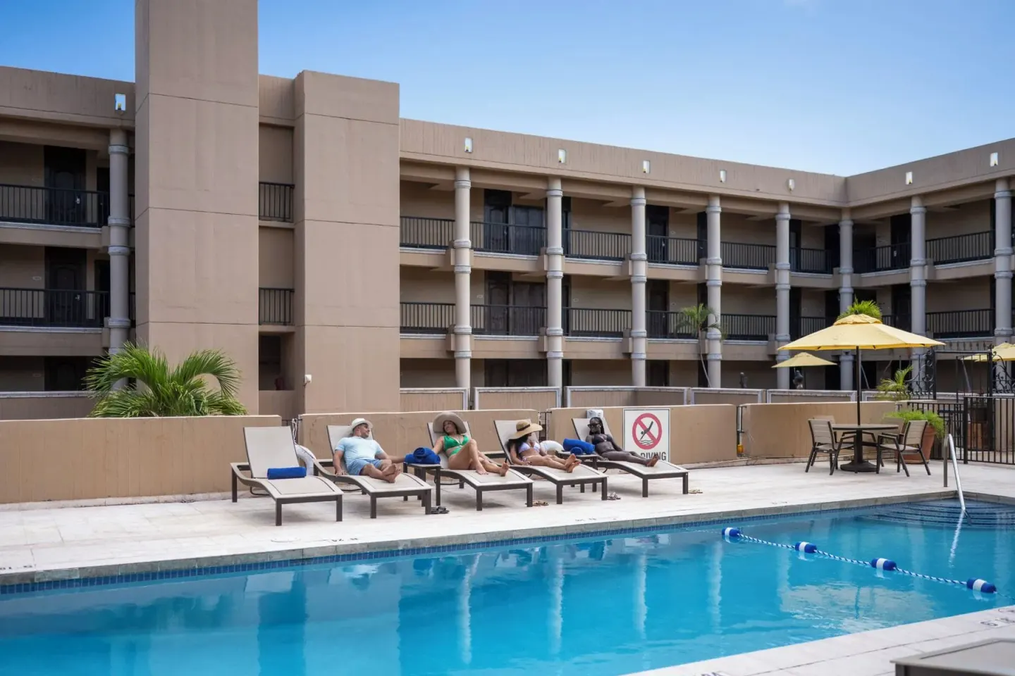Guests recline on poolside chaise lounges at Windward Passage Hotel.