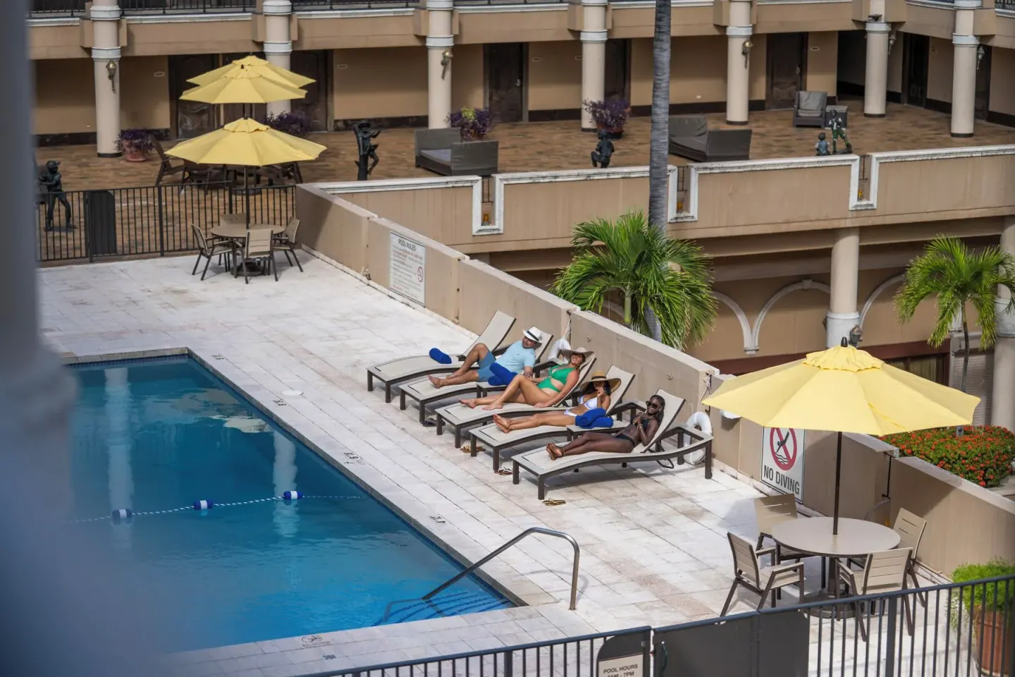 Guests relax on lounge chairs beside the courtyard pool at Windward Passage Hotel.