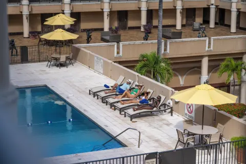Guests relax on lounge chairs beside the courtyard pool at Windward Passage Hotel.