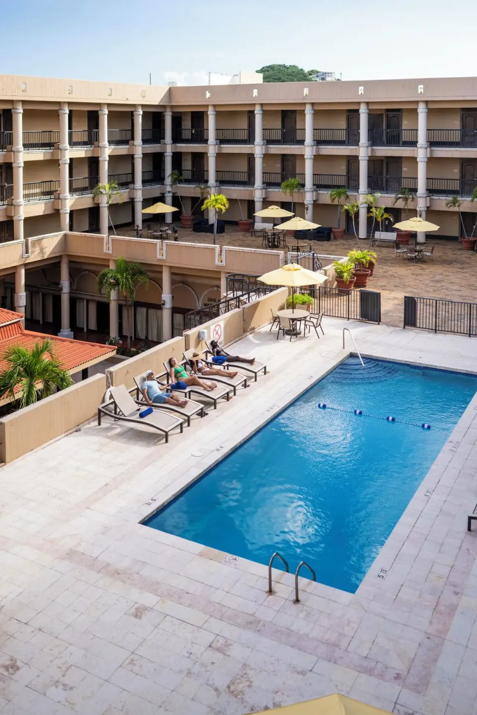 Guests sunbathe beside the courtyard pool at Windward Passage Hotel.
