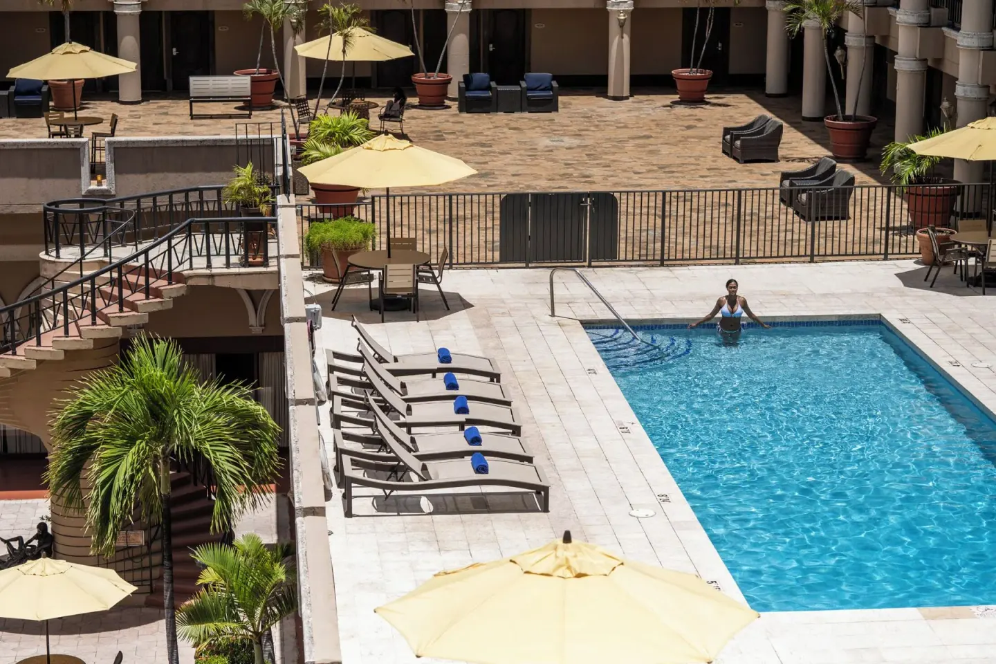 Poolside loungers, palms, and umbrellas surround the pool at Windward Passage Hotel.