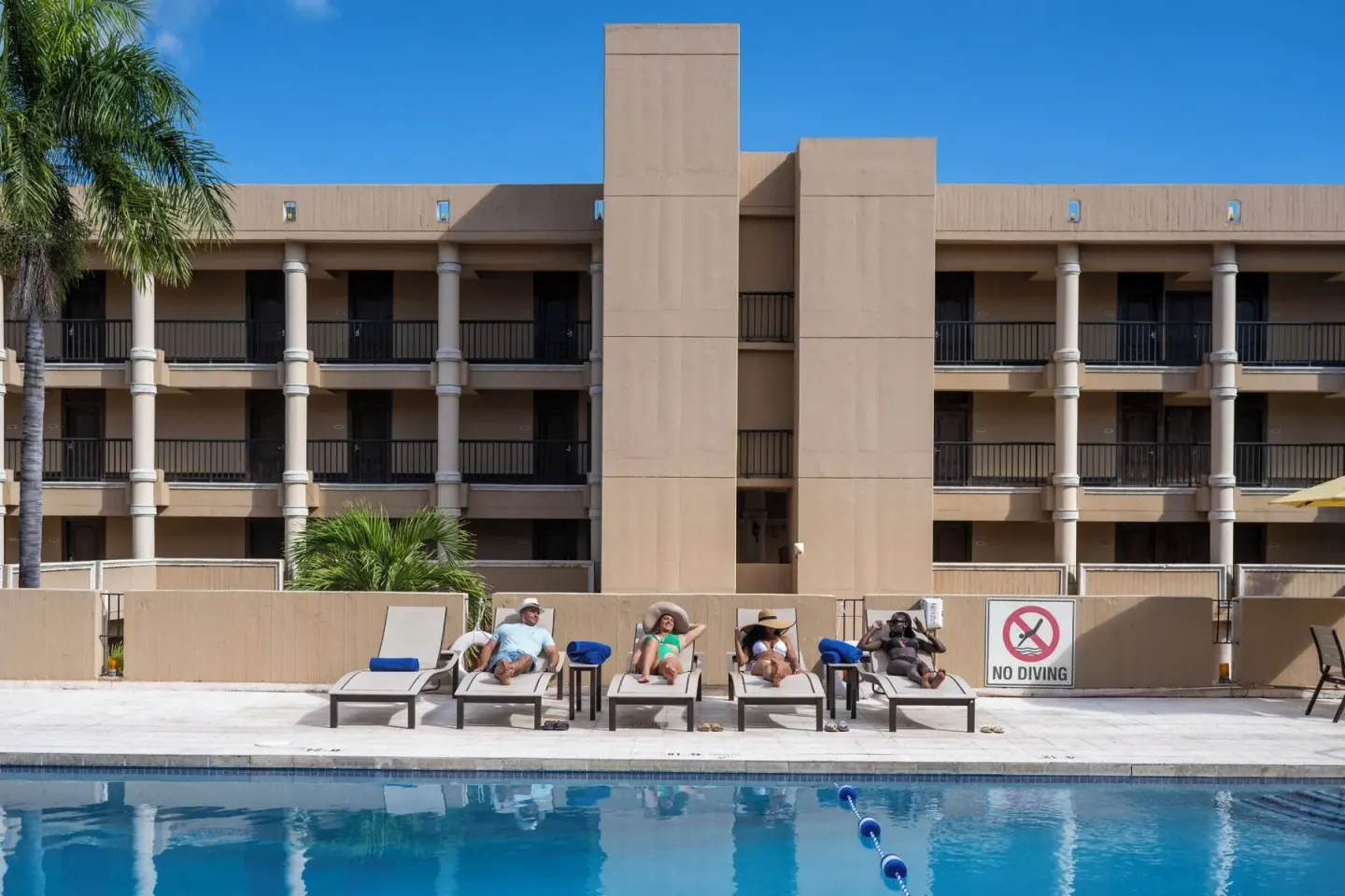 Guests sunbathe on loungers beside the pool at Windward Passage Hotel.