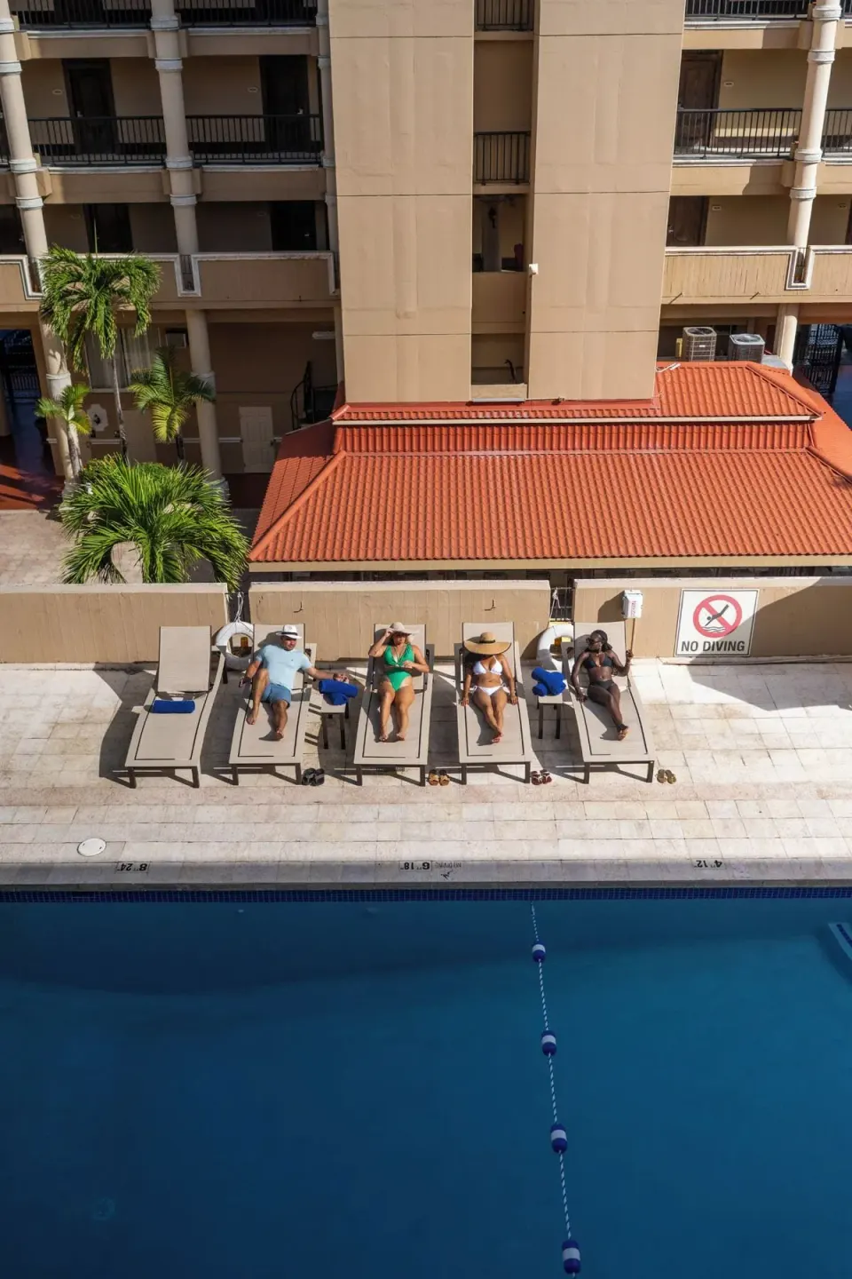 Vertical overhead view of poolside loungers and blue water at Windward Passage Hotel.