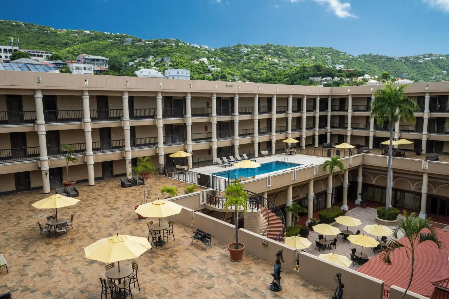 Wide view of the courtyard pool and hillside beyond Windward Passage Hotel.
