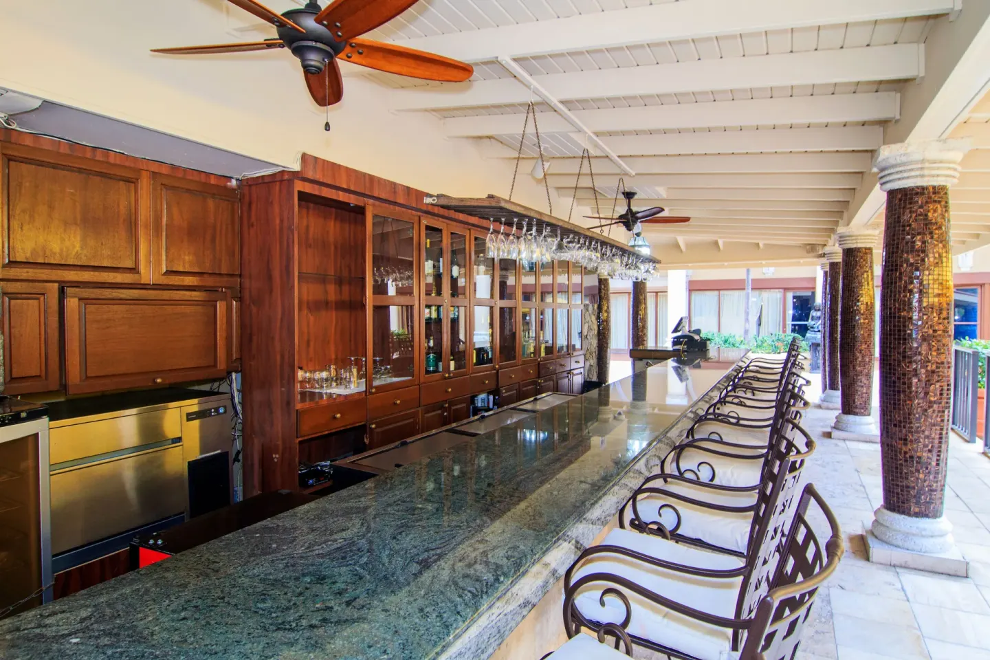 Covered bar with stone counter and high-back stools at Windward Passage Hotel.