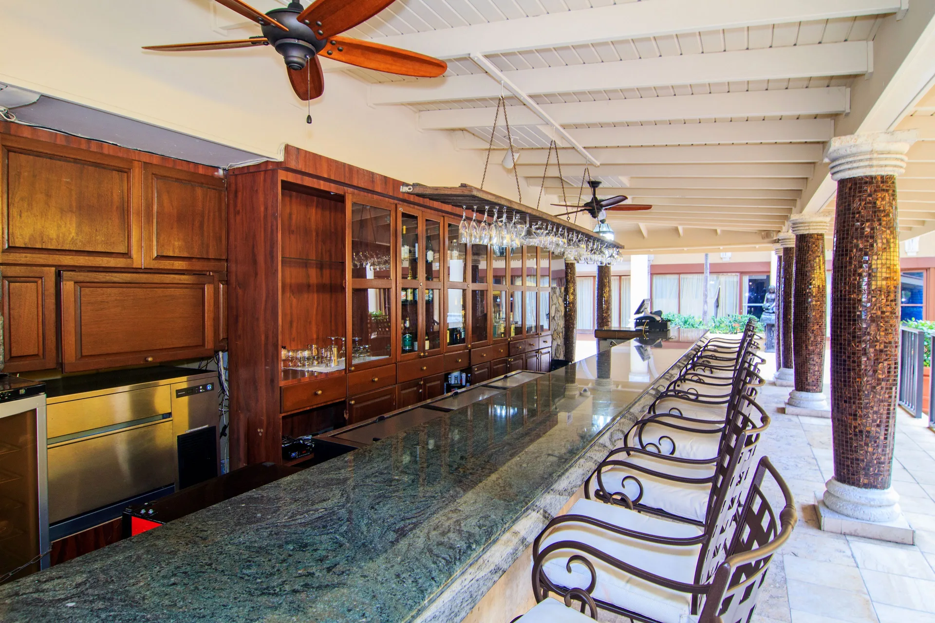 Covered bar with stone counter and high-back stools at Windward Passage Hotel.